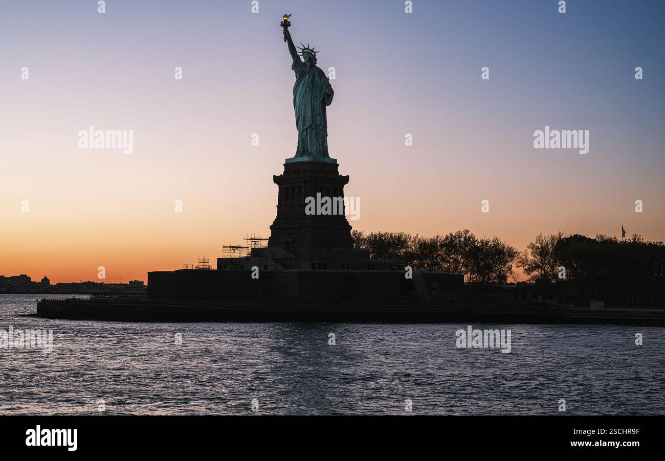 Au coucher du soleil, une silhouette époustouflante de la Statue de la liberté se dresse sur Liberty Island, New York. Le monument emblématique symbolise la liberté et l’espoir. Banque D'Images