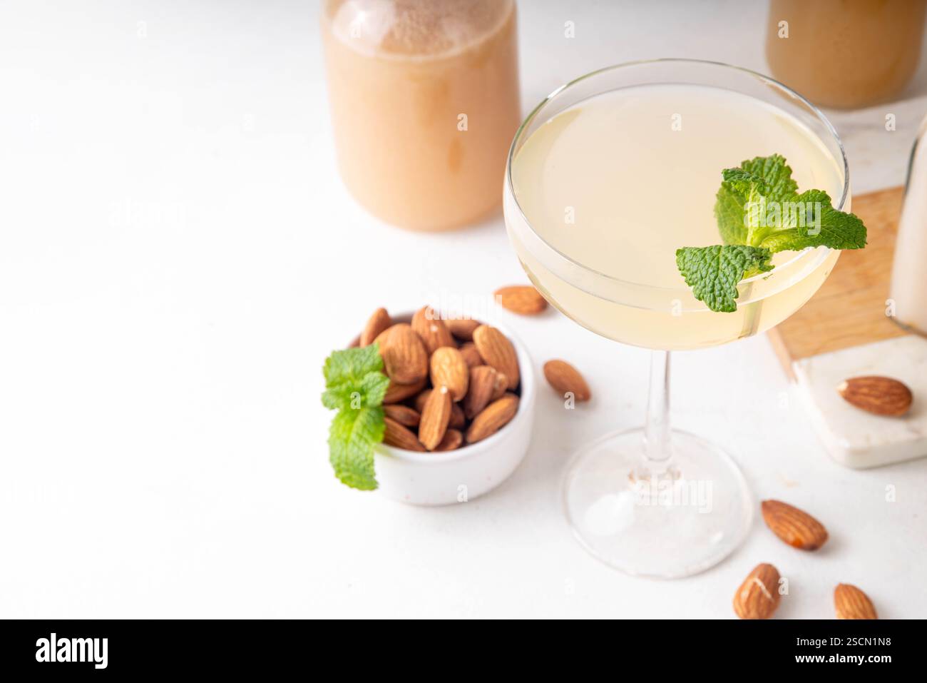 Cocktail d'orgeat au citron aigre-doux, recette de limonade à l'orgeat, un verre à martini avec boisson alcoolisée et bouteille de sirop d'orgeat d'amande Banque D'Images