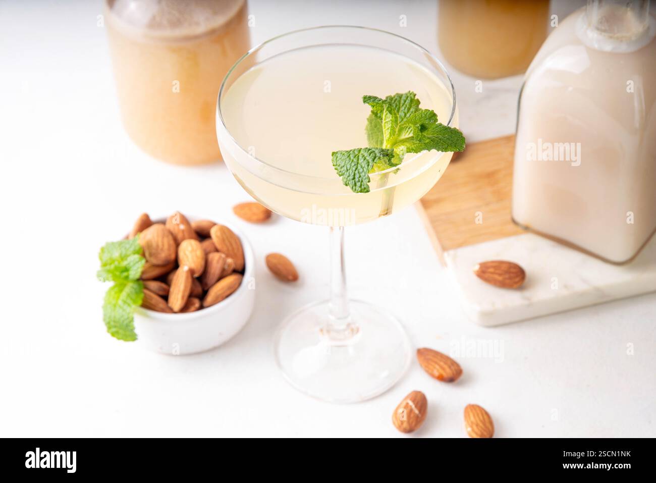 Cocktail d'orgeat au citron aigre-doux, recette de limonade à l'orgeat, un verre à martini avec boisson alcoolisée et bouteille de sirop d'orgeat d'amande Banque D'Images