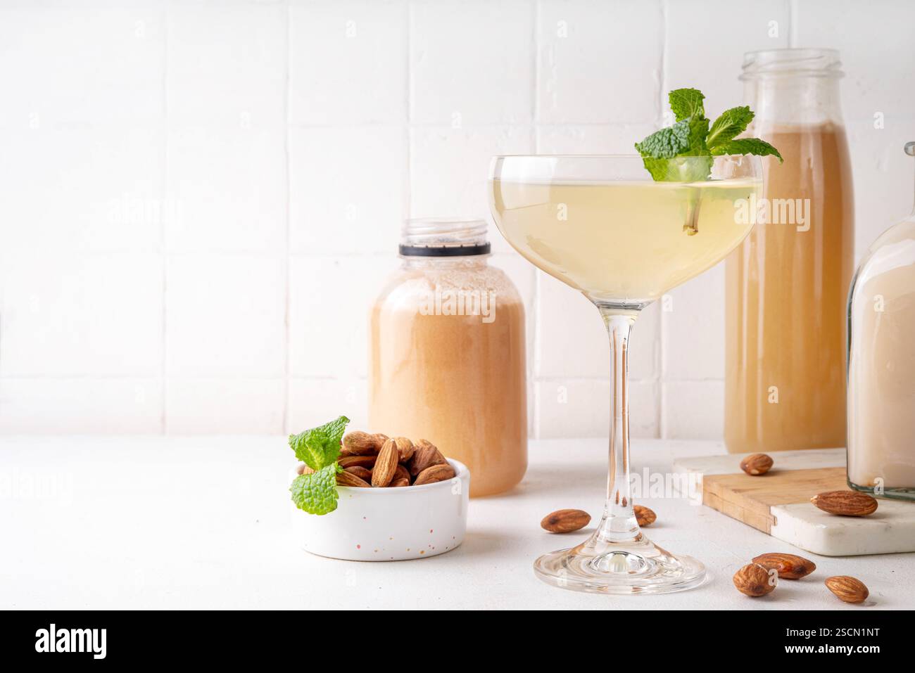 Cocktail d'orgeat au citron aigre-doux, recette de limonade à l'orgeat, un verre à martini avec boisson alcoolisée et bouteille de sirop d'orgeat d'amande Banque D'Images
