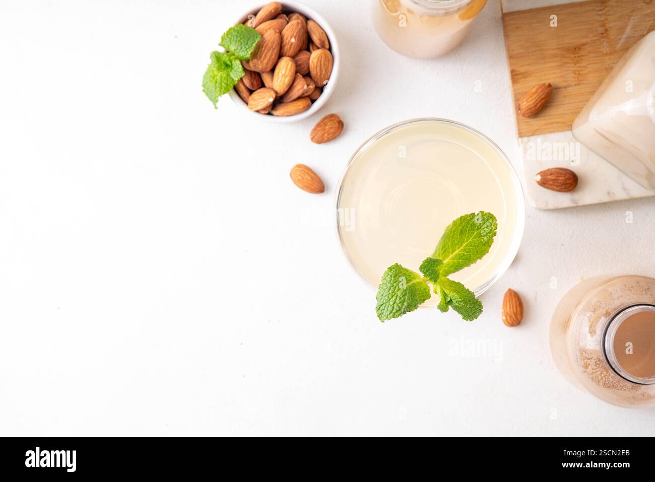 Cocktail d'orgeat au citron aigre-doux, recette de limonade à l'orgeat, un verre à martini avec boisson alcoolisée et bouteille de sirop d'orgeat d'amande Banque D'Images