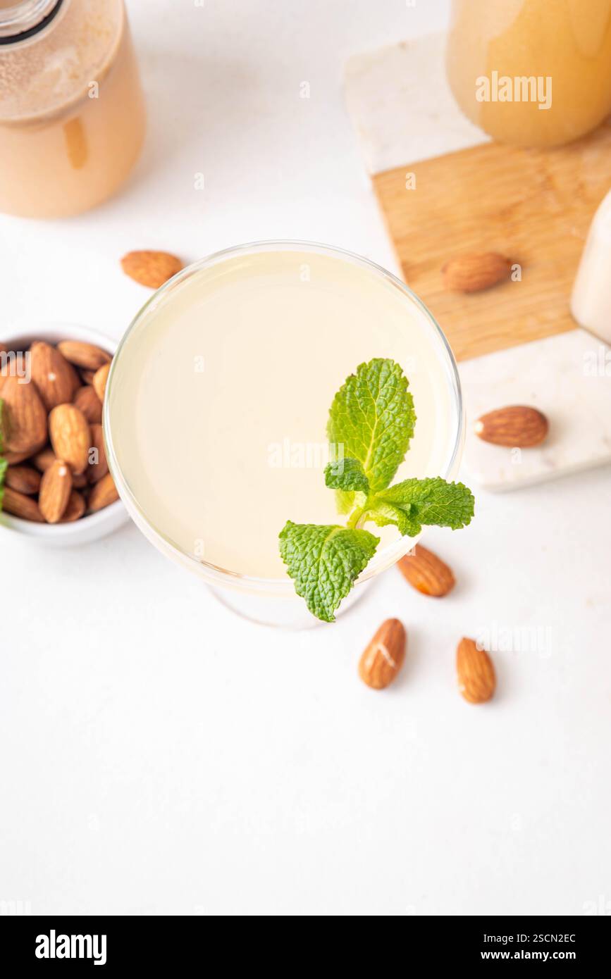 Cocktail d'orgeat au citron aigre-doux, recette de limonade à l'orgeat, un verre à martini avec boisson alcoolisée et bouteille de sirop d'orgeat d'amande Banque D'Images