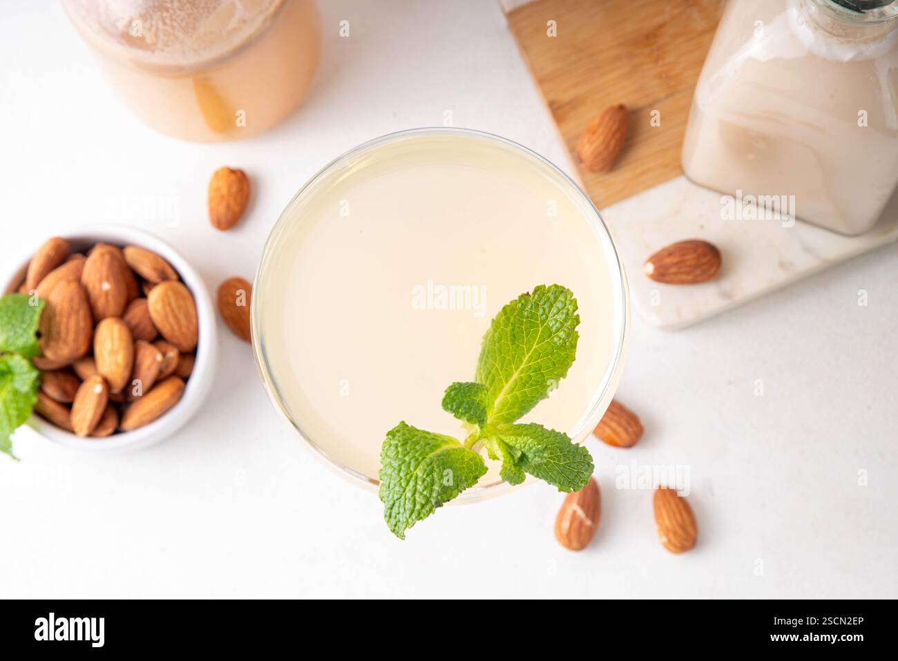 Cocktail d'orgeat au citron aigre-doux, recette de limonade à l'orgeat, un verre à martini avec boisson alcoolisée et bouteille de sirop d'orgeat d'amande Banque D'Images