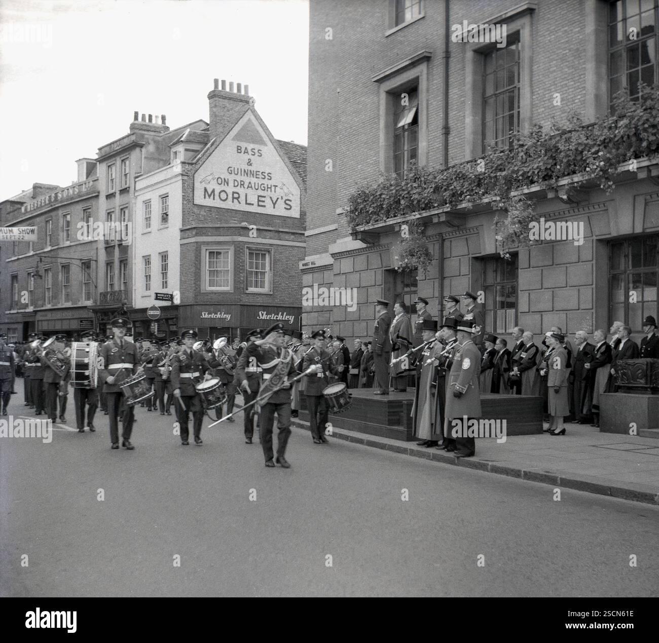 1960s, historique, un groupe militaire célébrant le jour 'A Best of British' défilant devant le coin de Petty Cury et le Guildhall, Cambridge, Angleterre, Royaume-Uni, surveillé par le maire local et des fonctionnaires. Bass Beer & Gunness on Draught au Morley's Wine Bar est écrit sur le mur latéral d'un bâtiment à Petty Cury au-dessus d'un Sketchely Dry Cleaners de l'époque. Banque D'Images