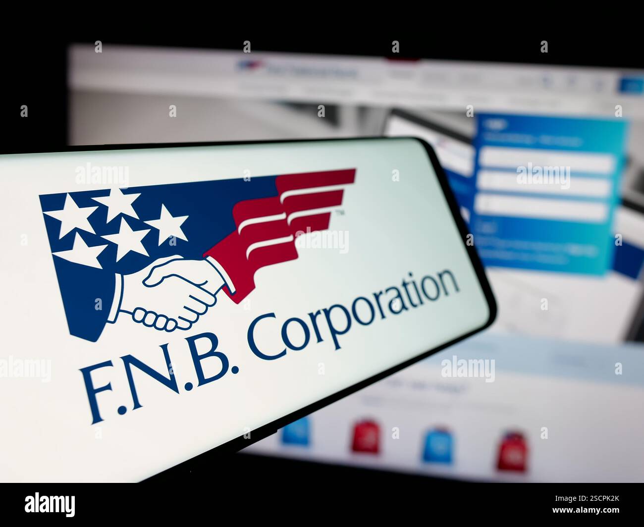 Dans cette illustration photo, un téléphone portable avec le logo de la société américaine FNB Corporation (First National Bank) est vu sur l'écran devant le site. Banque D'Images