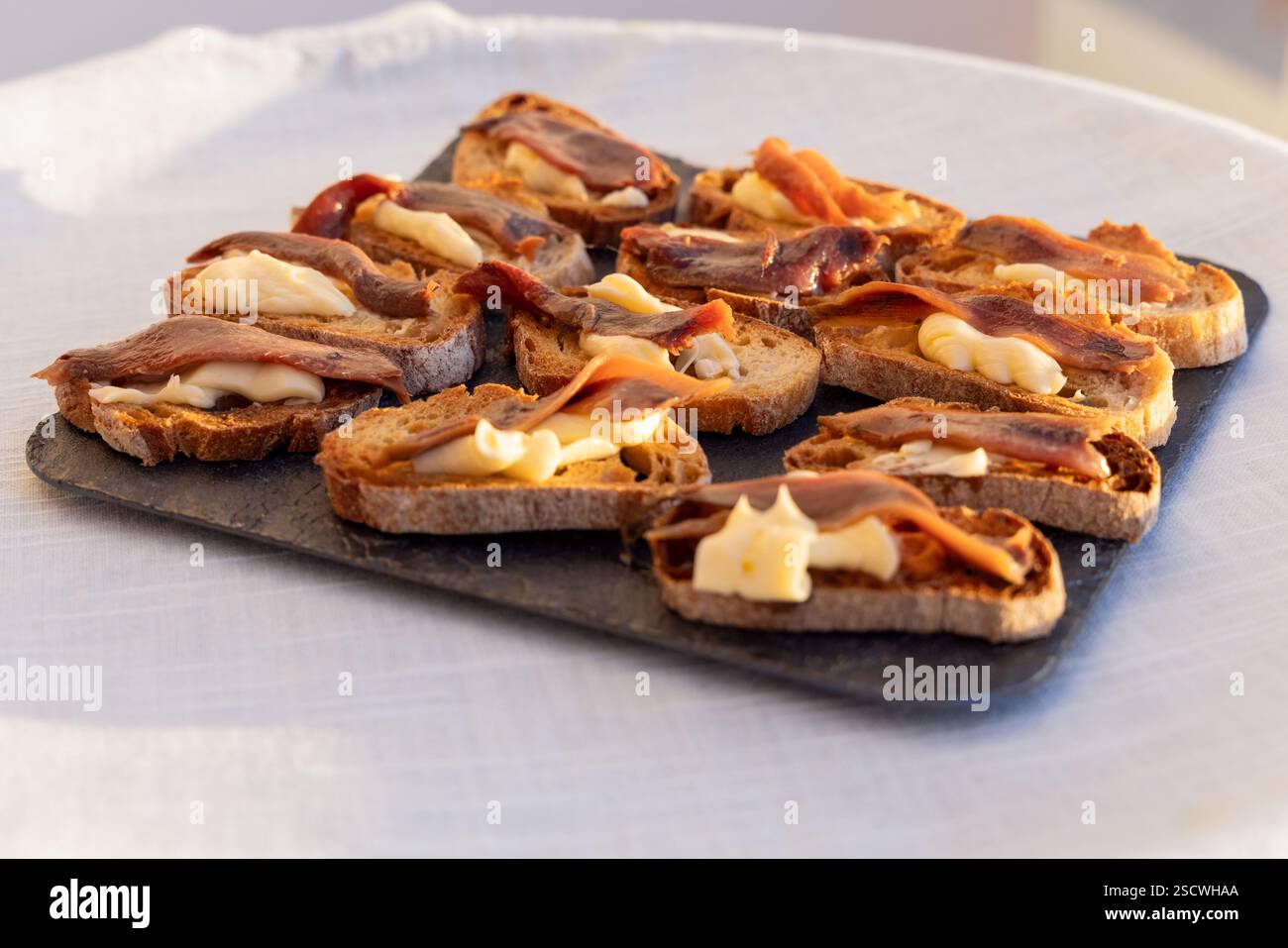 Entrées de pain grillé, beurre onctueux et anchois cantabriques, idéales pour les occasions gastronomiques et les rassemblements sophistiqués. Banque D'Images