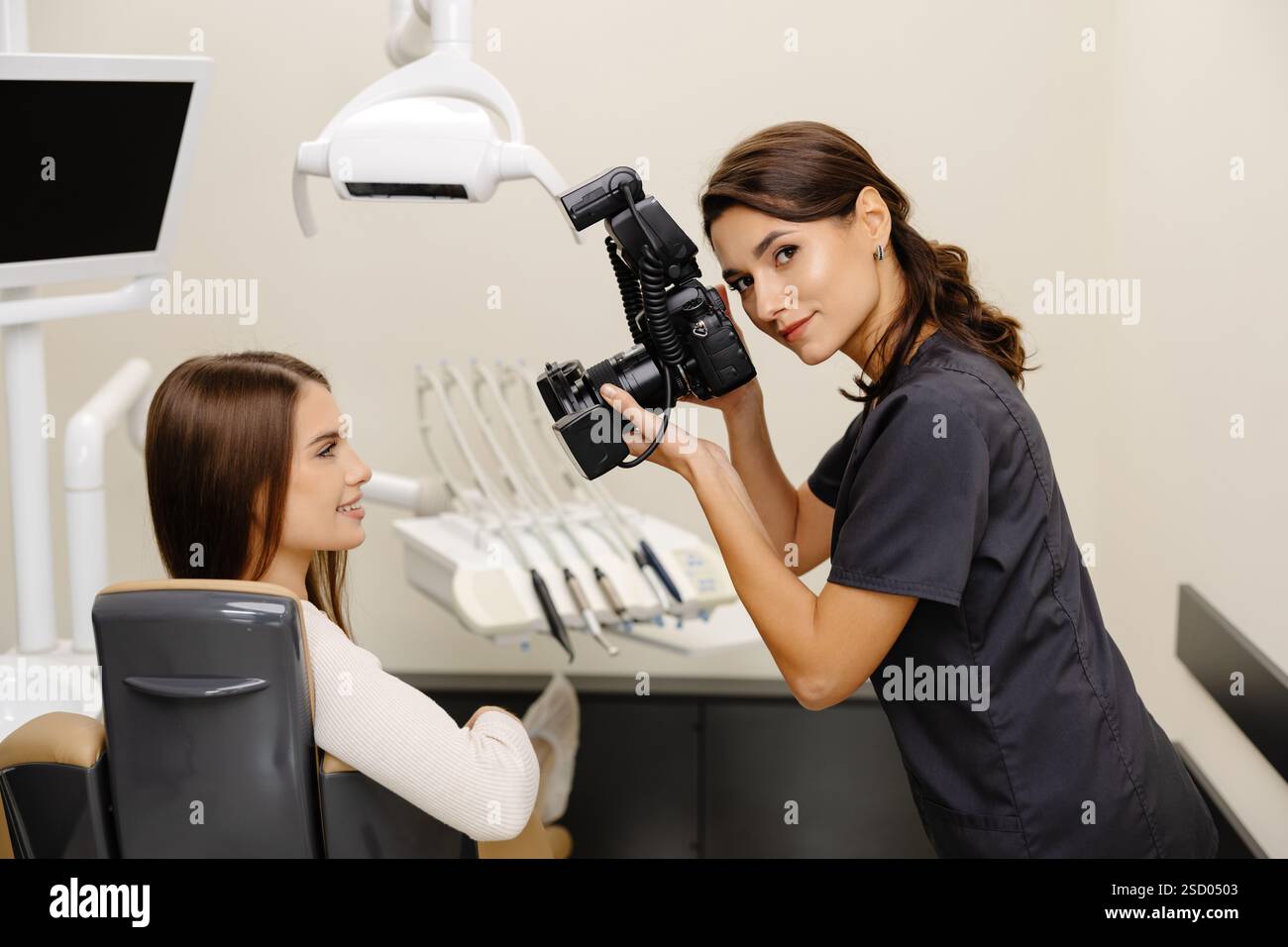 Femme dentiste photographiant avec un appareil photo professionnel le résultat de son travail en clinique. Banque D'Images