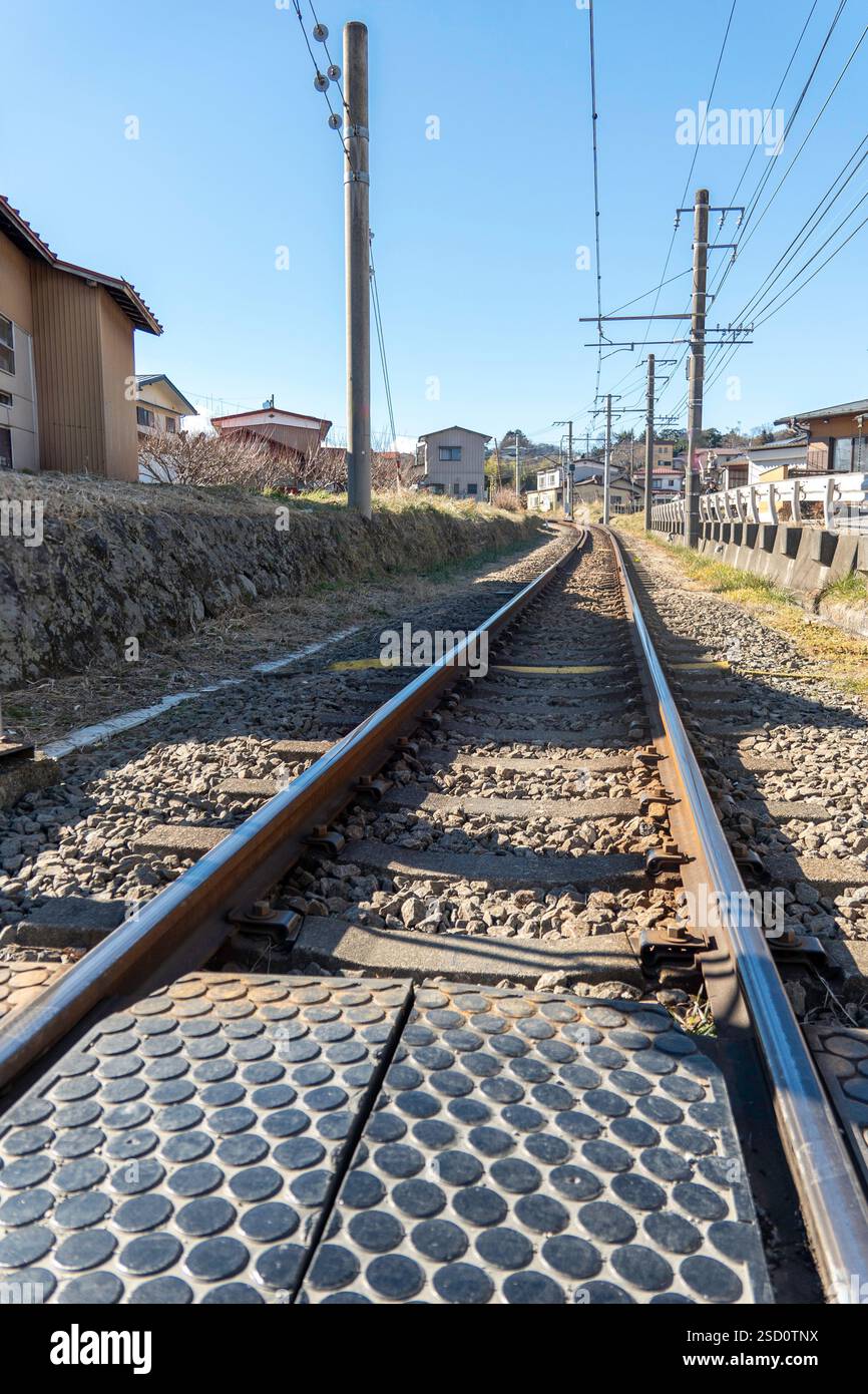 Gare au Japon avec plusieurs trains vintage et des montagnes pittoresques sous un ciel bleu Banque D'Images