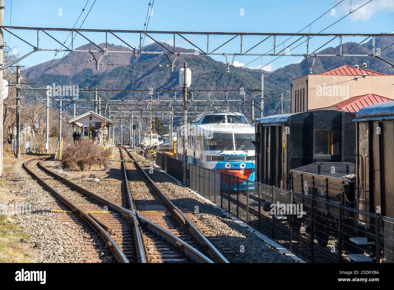 Gare au Japon avec plusieurs trains vintage et des montagnes pittoresques sous un ciel bleu Banque D'Images