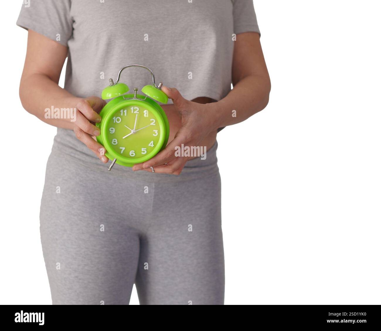 femme vêtue de vêtements de sport gris et d'un réveil vert. concept de jeûne intermittent. Banque D'Images