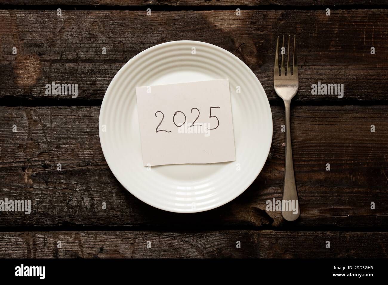 2025 écrit sur du papier couché sur une assiette sur un vieux tableau de bois gros plan Banque D'Images