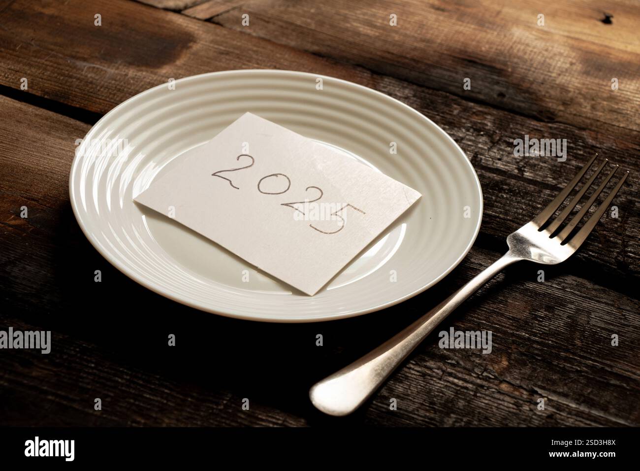 2025 écrit sur du papier couché sur une assiette sur un vieux tableau de bois gros plan Banque D'Images