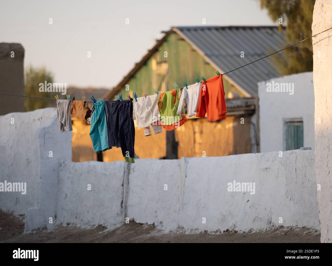 Vêtements colorés pour enfants fraîchement lavés accrochés à une corde à linge dans un village rural en Ouzbékistan. Banque D'Images