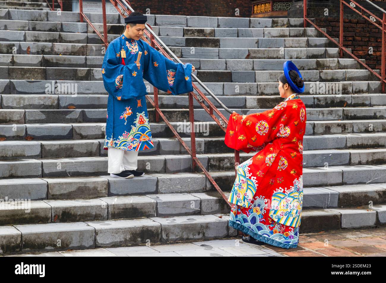 Couple vietnamien traditionnel en tenue colorée sur des marches de pierre au Mausolée tu Doc, Hue, Vietnam, lundi 04 novembre, 2024. photo : David Rowland Banque D'Images