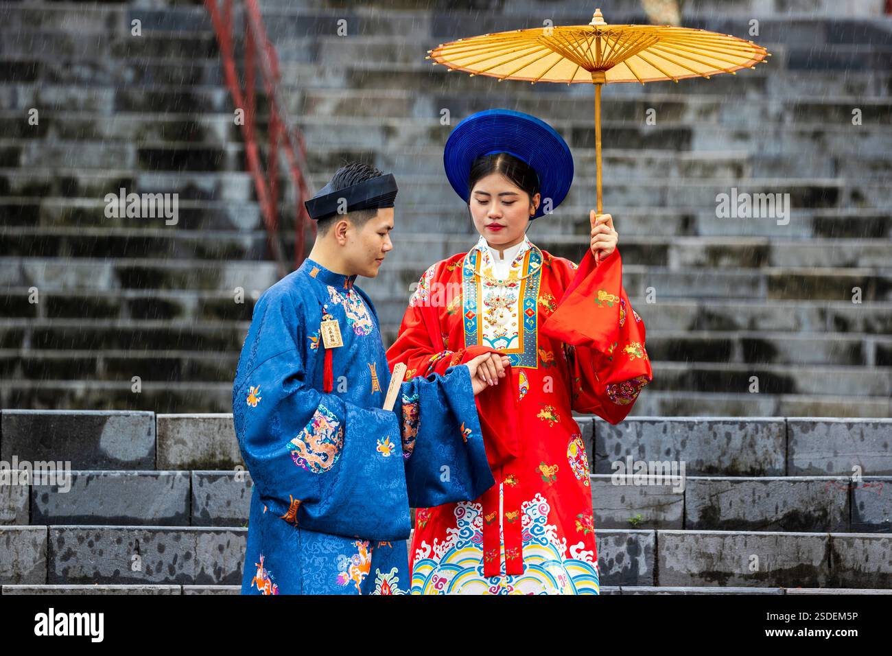 Couple vietnamien traditionnel en tenue colorée sur des marches de pierre au Mausolée tu Doc, Hue, Vietnam, lundi 04 novembre, 2024. photo : David Rowland Banque D'Images