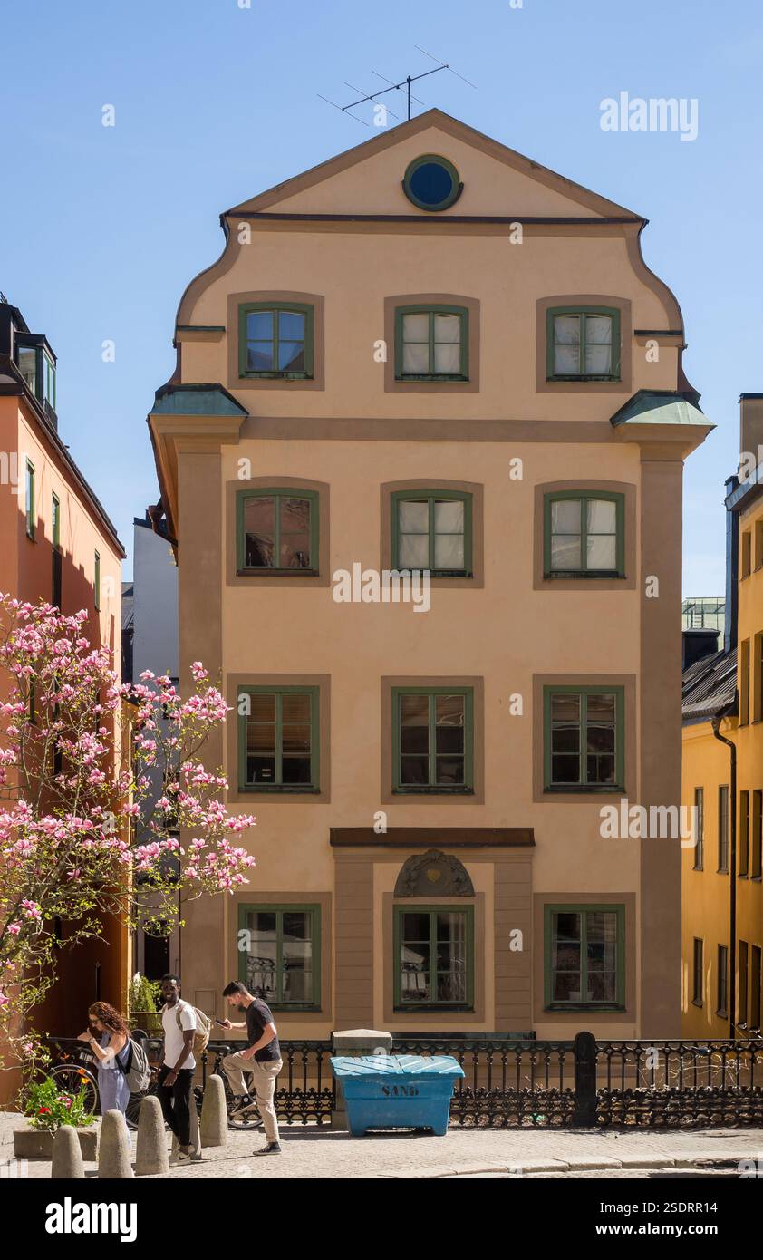 Un bâtiment de quatre étages dans un style architectural traditionnel, avec une façade peinte et au premier plan 3 jeunes profitant d'une journée ensoleillée d'été Banque D'Images