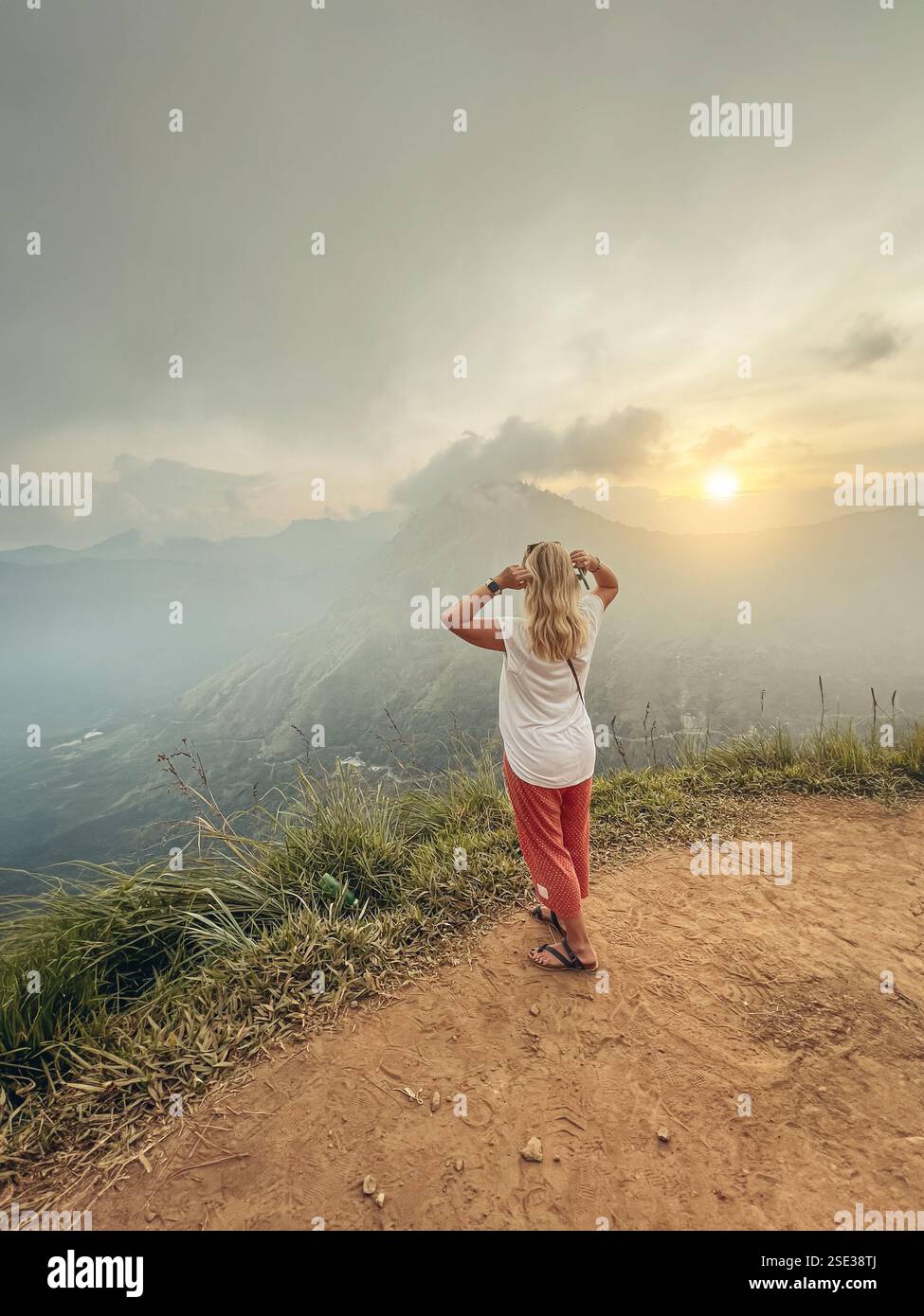 Une femme blonde profite du coucher de soleil et de la vue sur la montagne à Little Adam's Peak sur l'île du Sri Lanka Banque D'Images
