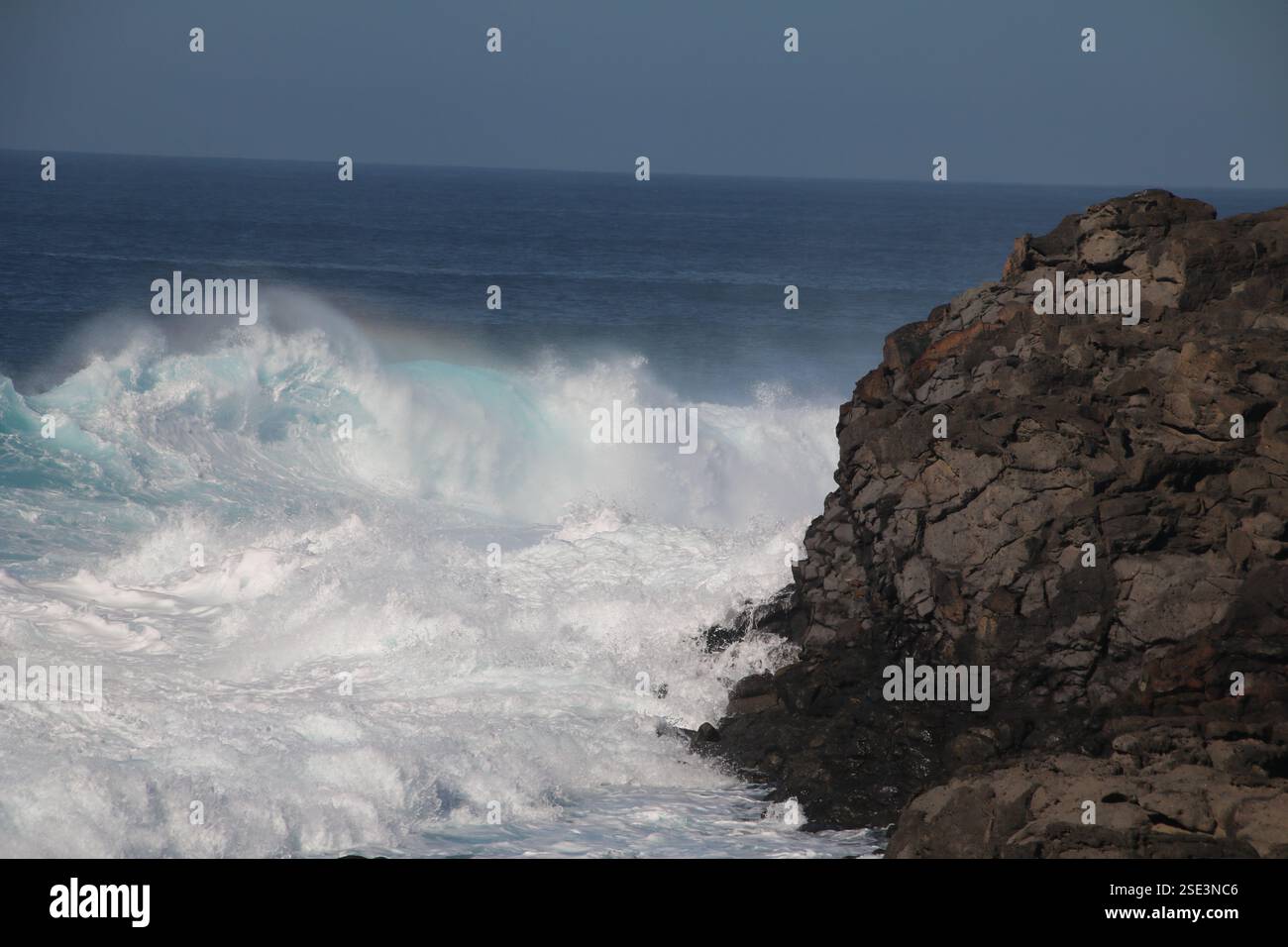 vagues de mer agitées s'écrasant sur les rochers causant l'effet arc-en-ciel Banque D'Images