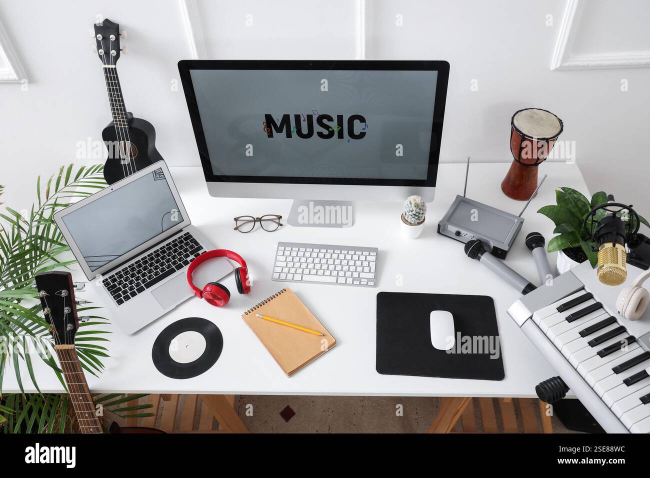 Lieu de travail avec ordinateur et instruments de musique près du mur lumineux dans le studio, vue de dessus Banque D'Images
