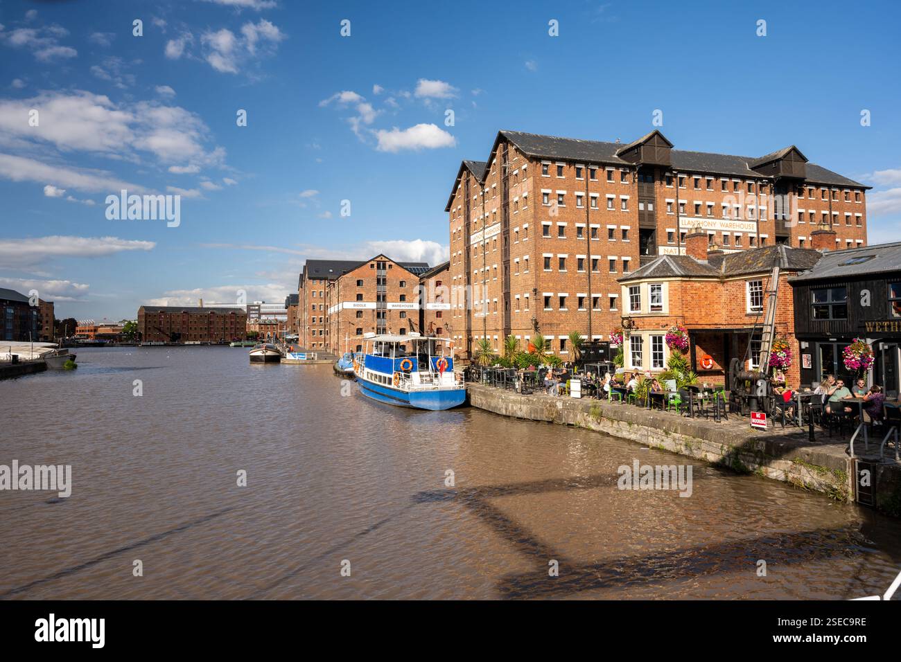 Les gens boivent dans un pub sur les quais régénérés des quais de Gloucester, sous les entrepôts de briques victoriens maintenant convertis en offense résidentielle à usage mixte Banque D'Images