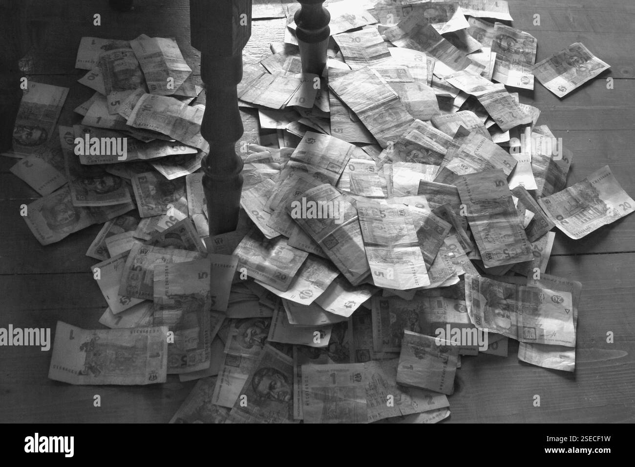 les vieux billets de papier sont jetés dans une pile sur le sol près du pied de la table Banque D'Images