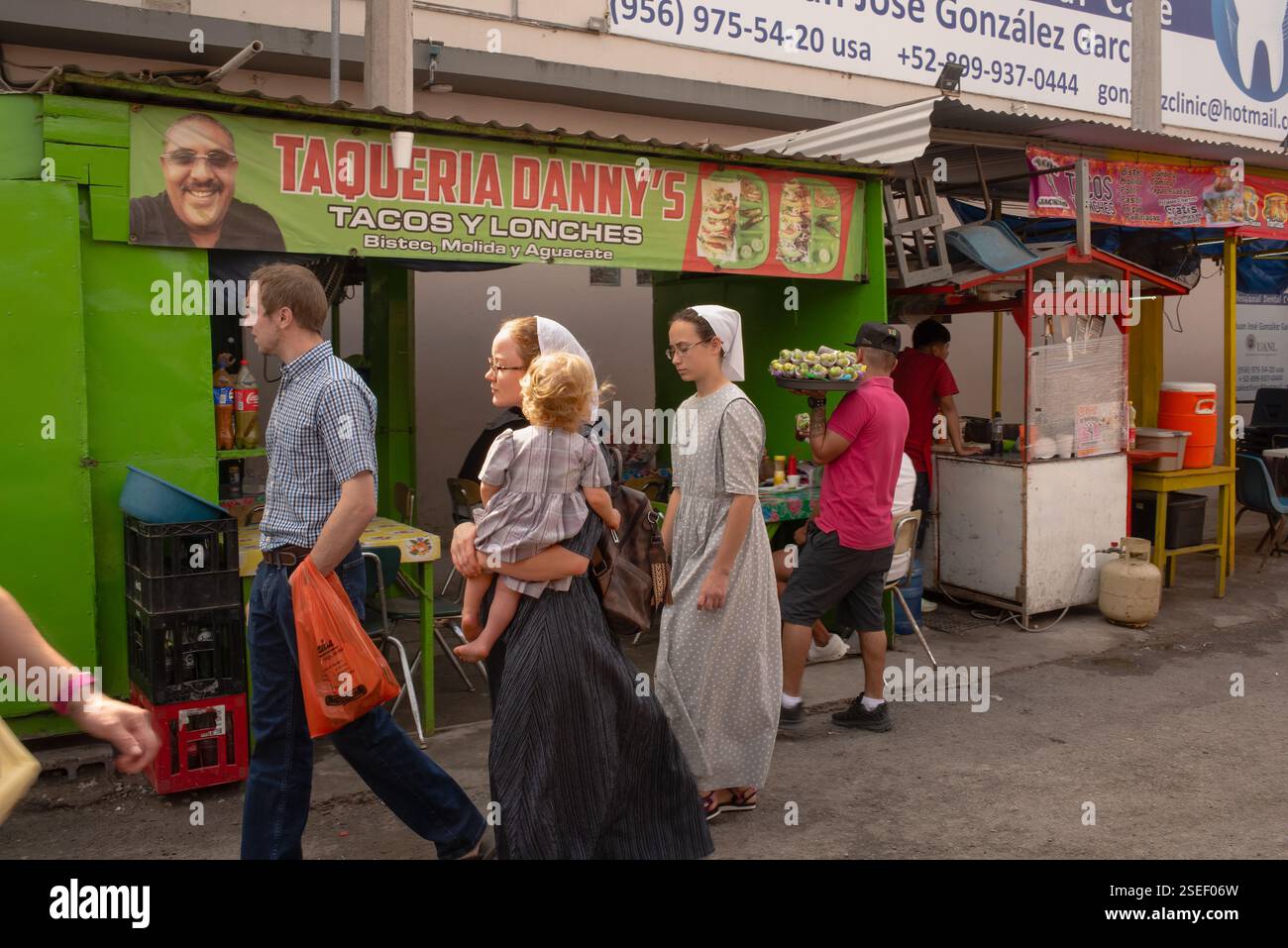 Homme avec deux femmes en tenue religieuse, peut-être mormon, dont une portant un bébé, marchant dans la rue de la ville frontalière de Nuevo Progreso, au Mexique. Banque D'Images