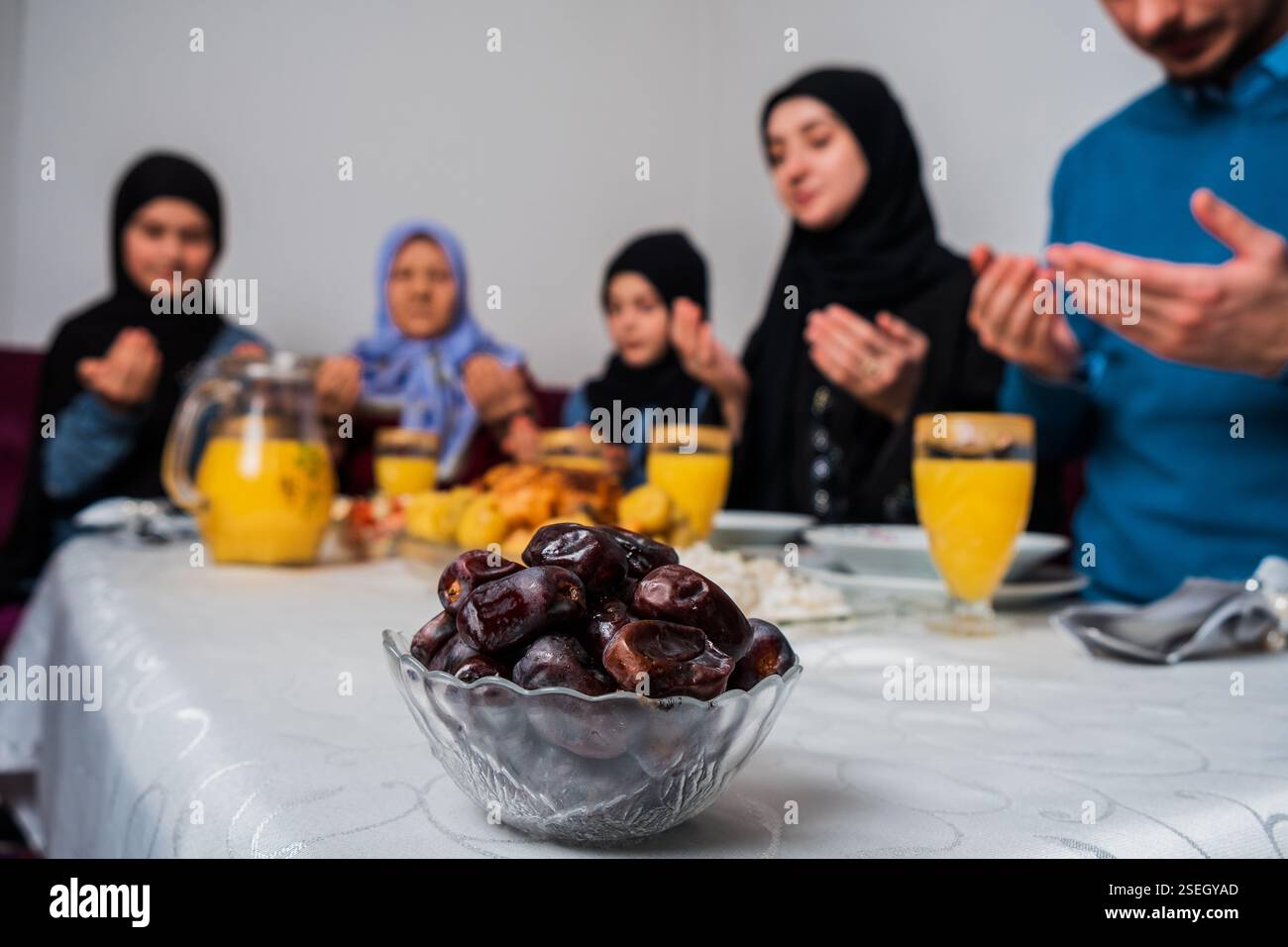 Heureuse famille musulmane ensemble faire iftar dua pour faire la pause jeûne pendant le Ramadan à la table à manger à la maison se concentrer sur un bol de dates nutrition saine Banque D'Images