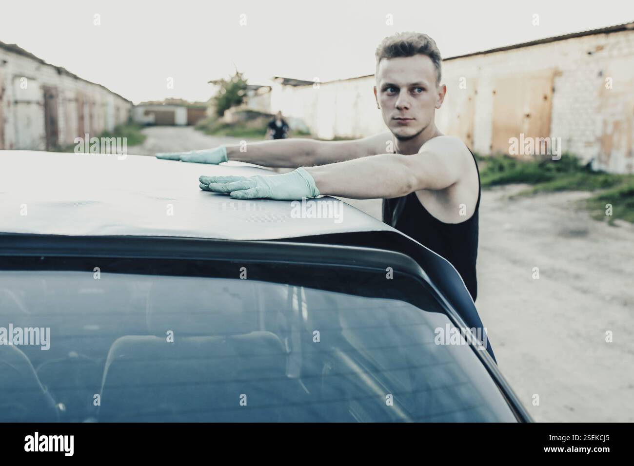 Homme concentré sur une tâche impliquant une voiture dans un environnement de garage Banque D'Images