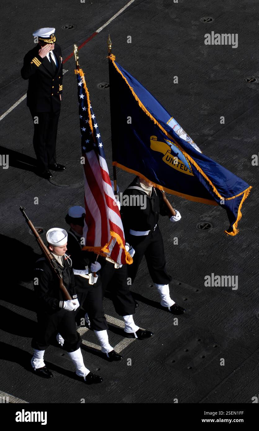 Le président d'audience Cmdt. Mitchell Kloewer, top, d'Albany, Oregon, salue alors que le gardien de couleur retire les couleurs à la fin d'une cérémonie d'enterrement en mer à bord du porte-avions USS John C. Stennis de classe Nimitz. Stennis est en transit vers le sud de la Californie pour soutenir les qualifications des pilotes de porte-avions pour les escadrons de remplacement de flotte et le commandement de l'entraînement aérien naval. Banque D'Images