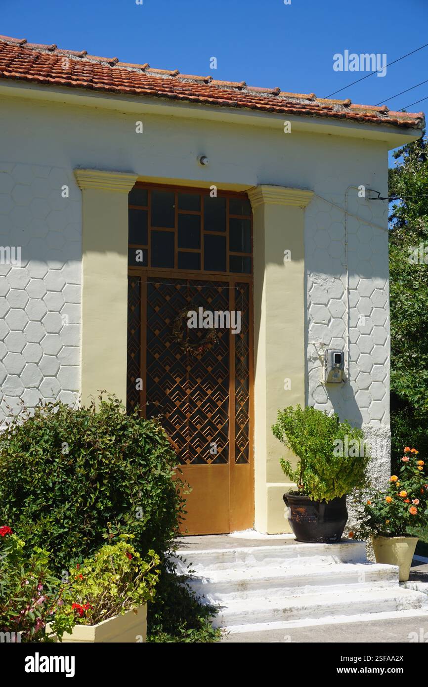 Un bâtiment traditionnel à la Canée avec un toit en tuiles et un beau jardin plein de fleurs et de plantes, un jeu traditionnel, « koutso » et une aire de jeux Banque D'Images