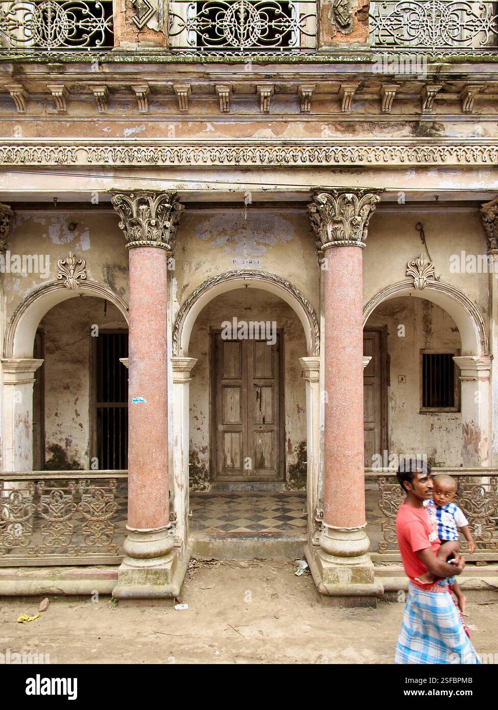 Un homme avec un garçon passe devant un manoir en décomposition à Panam City, Sonargaon, Bangladesh, un site historique reflétant l'architecture de l'époque coloniale. Banque D'Images