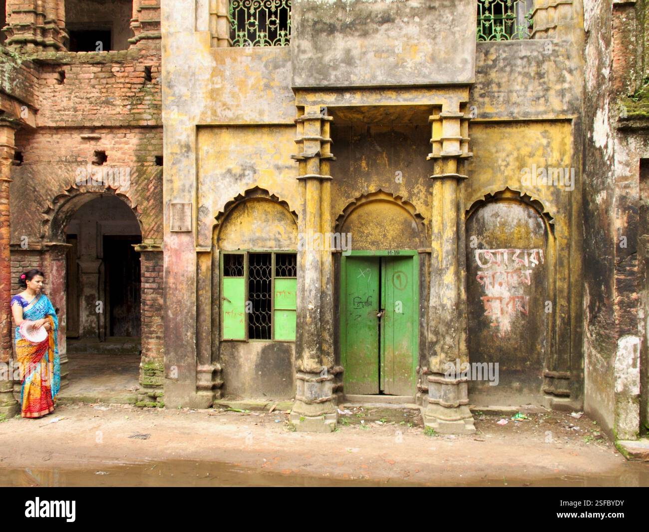 Une femme dans un sari attend à côté d'un manoir en décomposition à Panam City, Sonargaon, Bangladesh, un site historique reflétant l'architecture de l'époque coloniale Banque D'Images