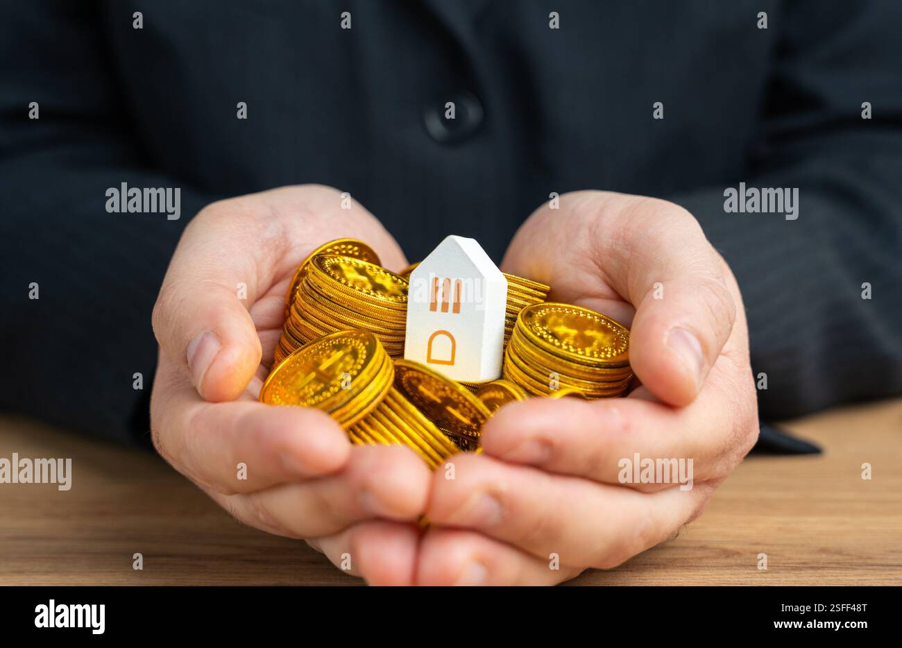 Maison sur une poignée de pièces de monnaie en mains. Prix du logement. Économisez pour acheter une maison. Contracter une hypothèque. Le coût de l'immobilier ou du terrain en dessous Banque D'Images