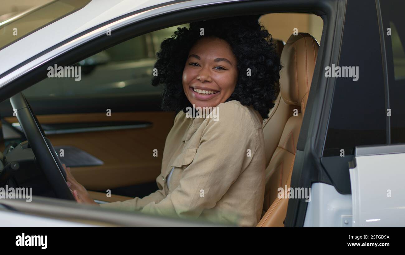 Excité femme heureuse cliente afro-américaine femme d'affaires fille souriante dame à l'intérieur de la nouvelle voiture agitant la main à la caméra riant automobile électrique moderne Banque D'Images