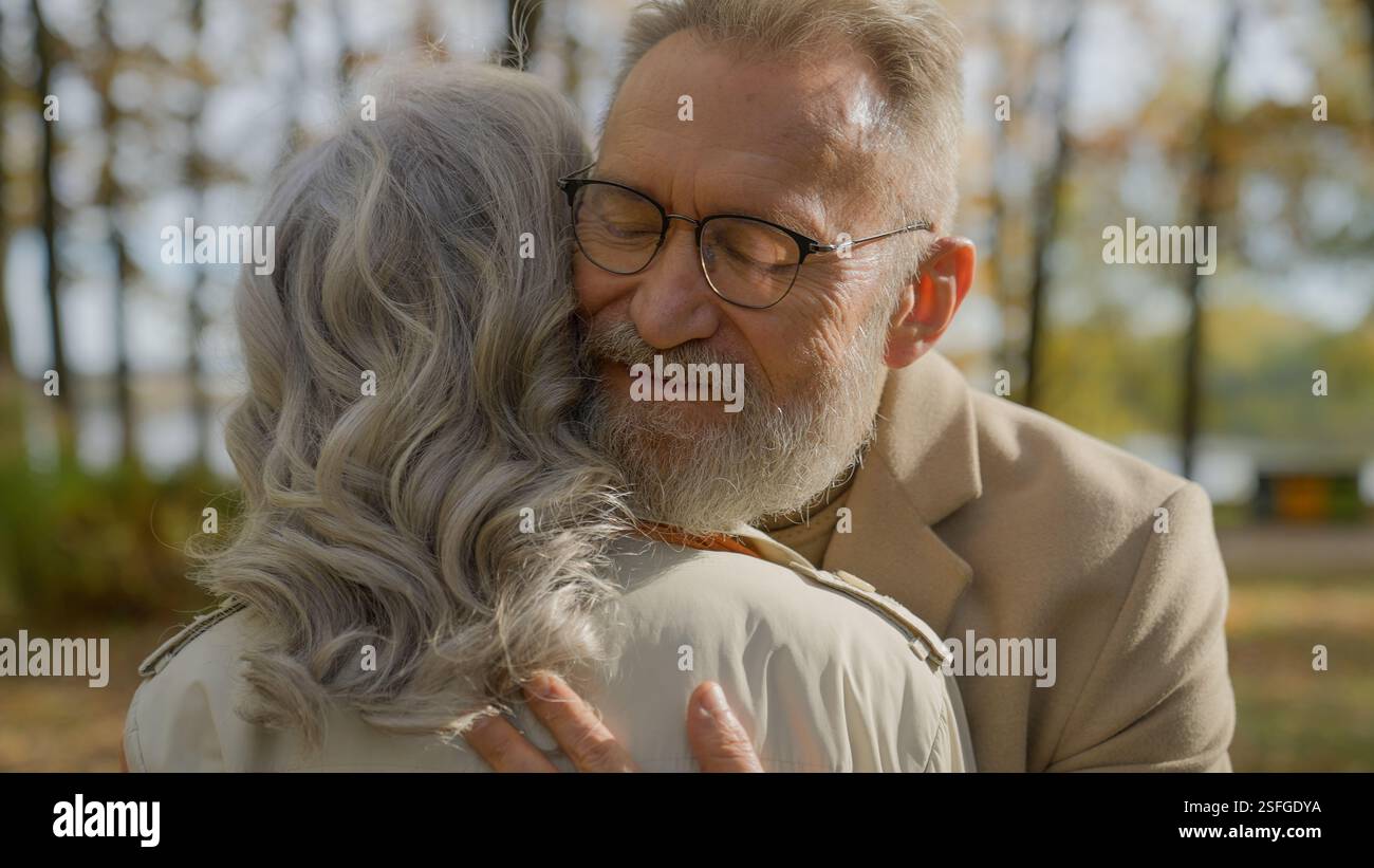 Couple mature embrassant dans le parc d'automne senior cheveux gris 60s homme âgé embrassant femme heureuse famille mariée embrasser embrasser Hug amour soutien de soin romance à vieux Banque D'Images