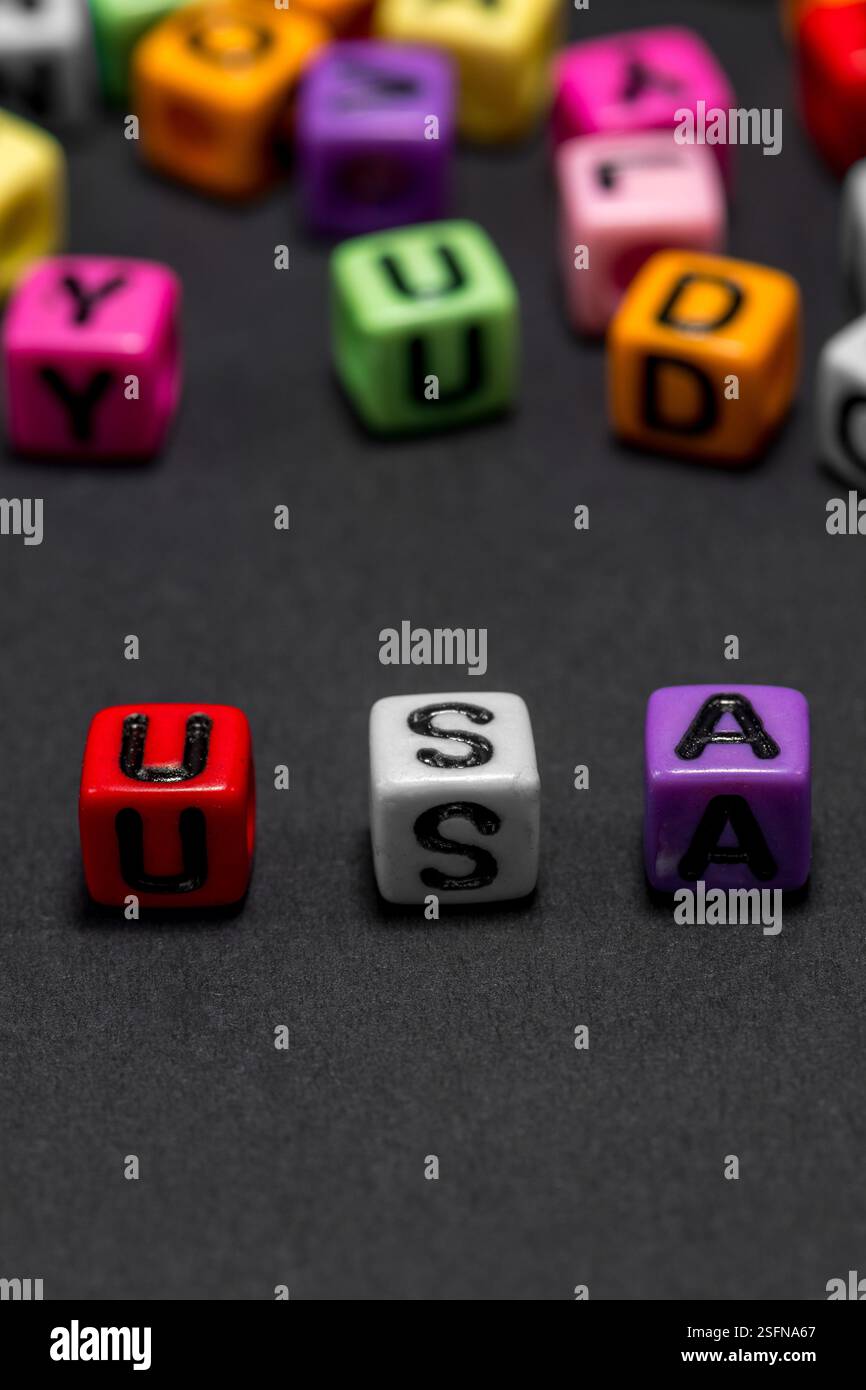 De petits cubes colorés avec des lettres de l'alphabet forment le mot 'USA' (États-Unis d'Amérique) au premier plan, fond noir, espace de copie. Banque D'Images
