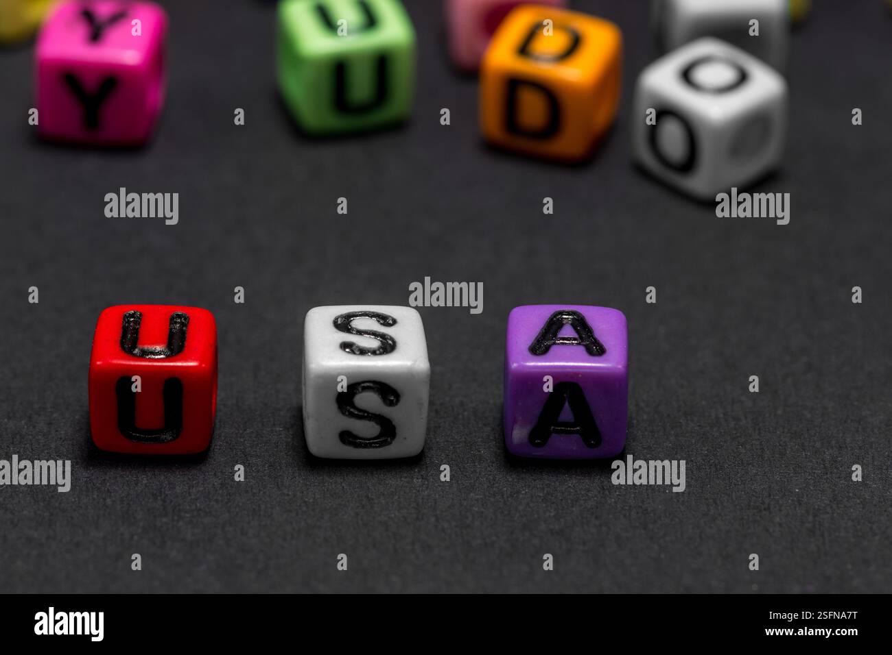 De petits cubes colorés avec des lettres de l'alphabet forment le mot 'USA' (États-Unis d'Amérique) au premier plan, fond noir, espace de copie. Banque D'Images