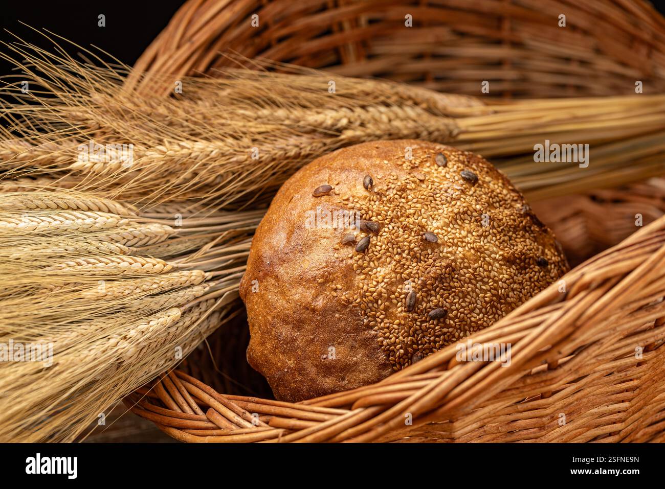 Pain rond recouvert de graines se trouve sur un panier, créant une scène de boulangerie rustique Banque D'Images