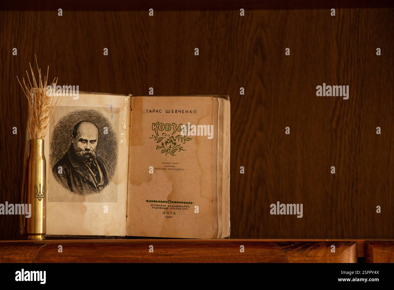 Ukraine Dnepr février 09, 2025 - Livre Kobzar Taras Shevchenko et un étui de cartouche avec les armoiries de l'Ukraine et une épi de blé sur une étagère Banque D'Images