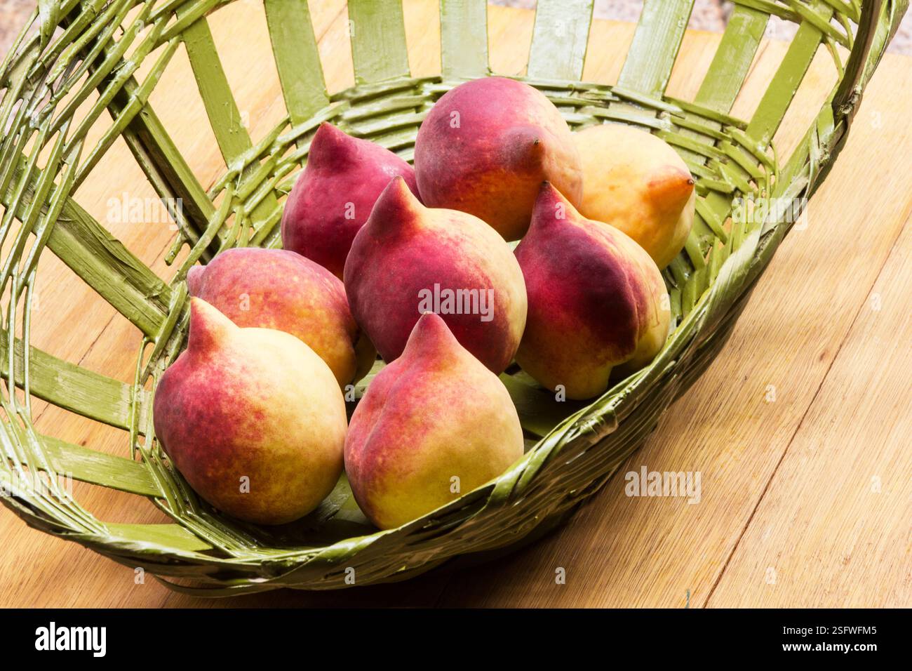 Belles pêches fraîches (Prunus persica) dans un panier sur un fond en bois Banque D'Images
