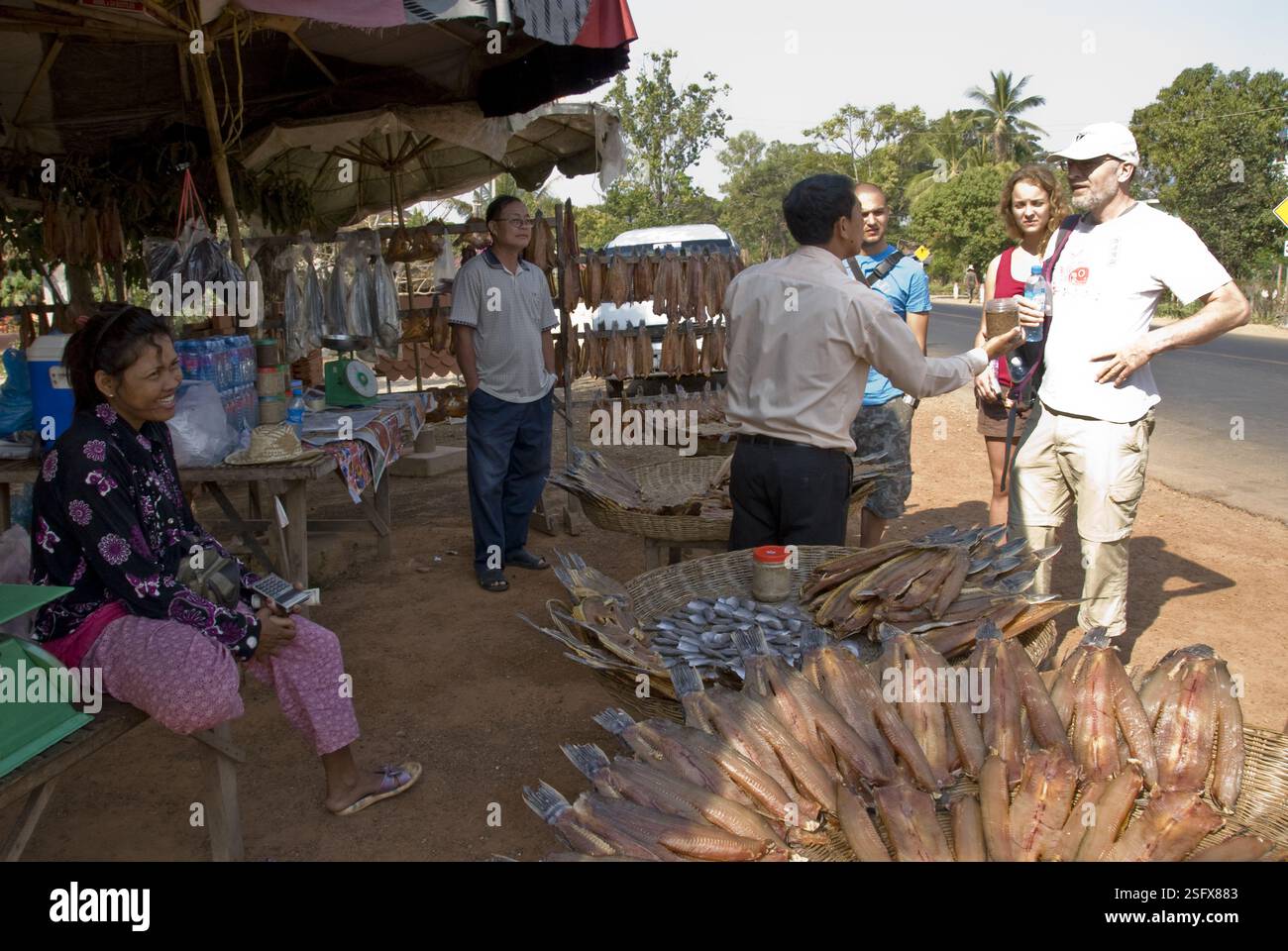 Guide décrit les produits aux touristes sur un marché en bord de route près du lac Tonle SAP, près de Siem Reap. Banque D'Images