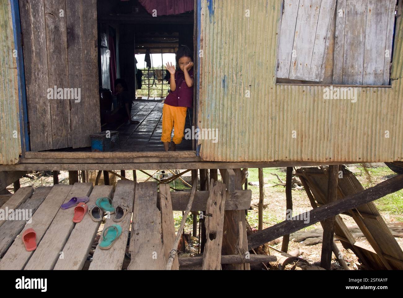Une petite fille fait des vagues depuis la porte de sa maison sur le lac Tonle SAP. Banque D'Images