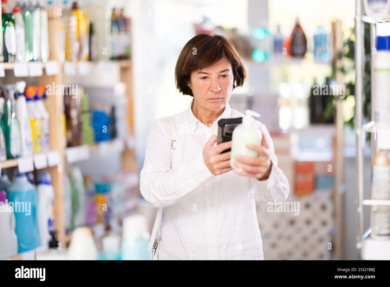 Femme âgée scannant le code qr pour le savon liquide Banque D'Images