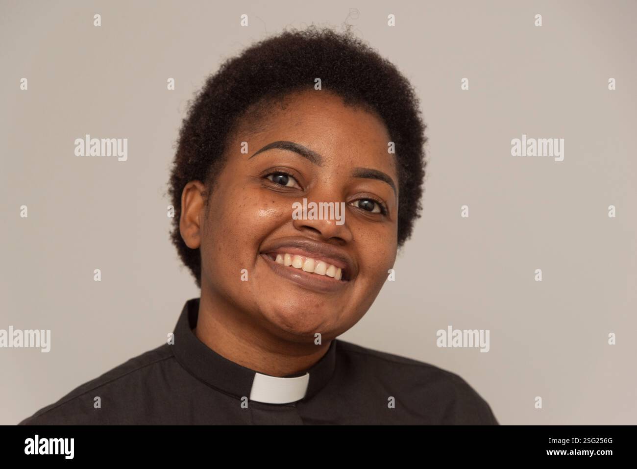 Angleterre Royaume-Uni. 26.01.2025. Portrait d’une femme africaine portant un col ecclésiastique blanc et une chemise noire. Banque D'Images