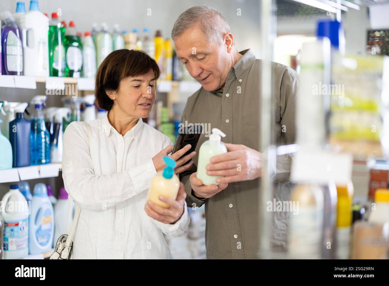 Couple homme et femme scannant le code qr pour le savon liquide Banque D'Images