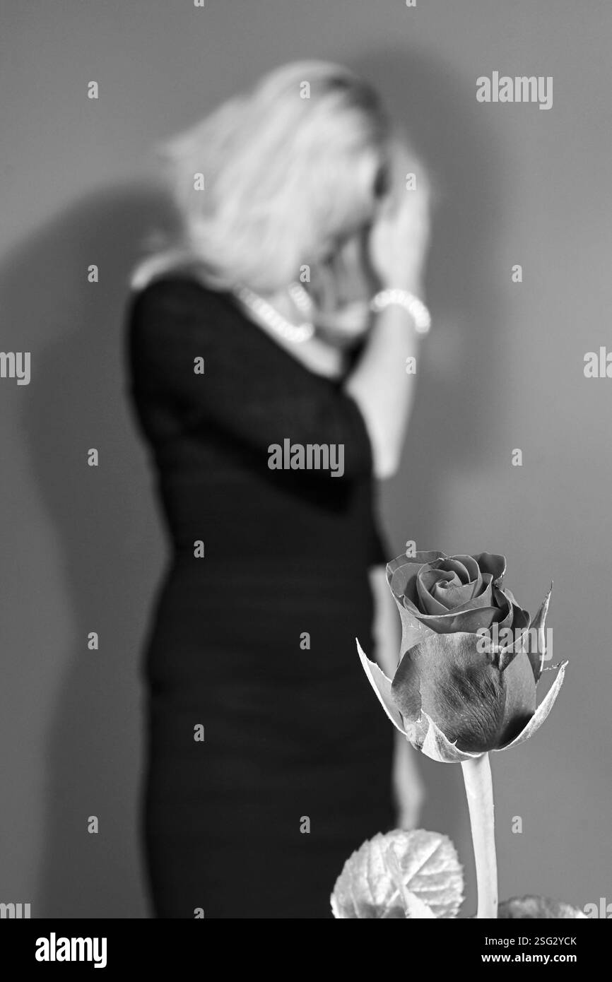 Rose rouge pour fille blonde en robe noire pour la Saint-Valentin, monochrome Banque D'Images