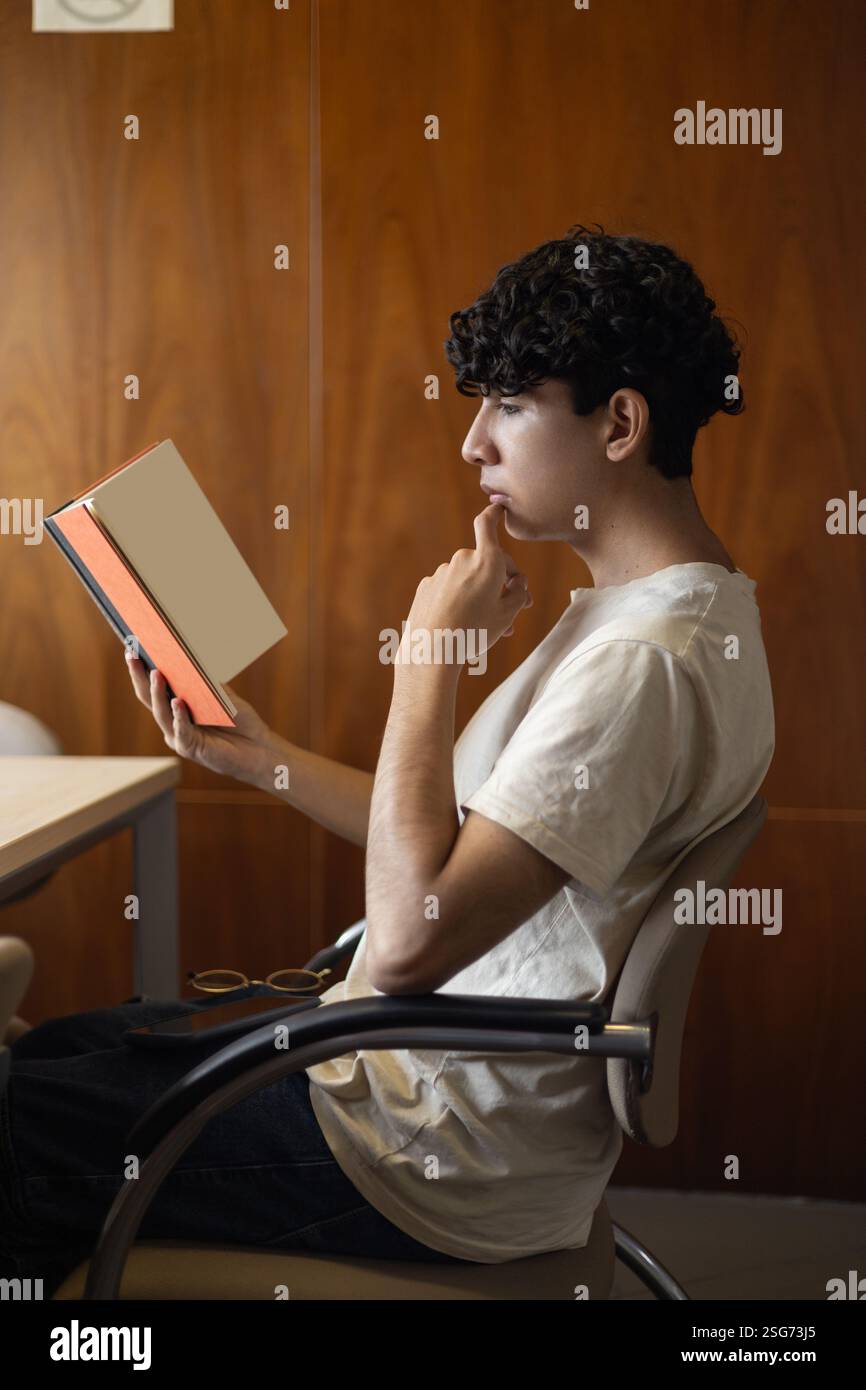 Une personne lisant et analysant un livre, axée sur la compréhension de son contenu. Idéal pour les thèmes d'étude, de croissance intellectuelle et d'analyse littéraire. Banque D'Images