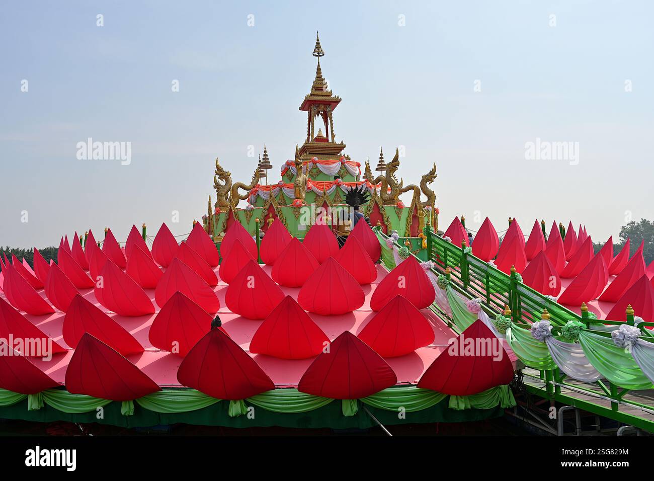 Des dévots qui respectent l'image de Bouddha sur le sanctuaire flottant de lotus rouge vif à Wat Saman Rattanaram à Chachoengsao, Thaïlande Banque D'Images