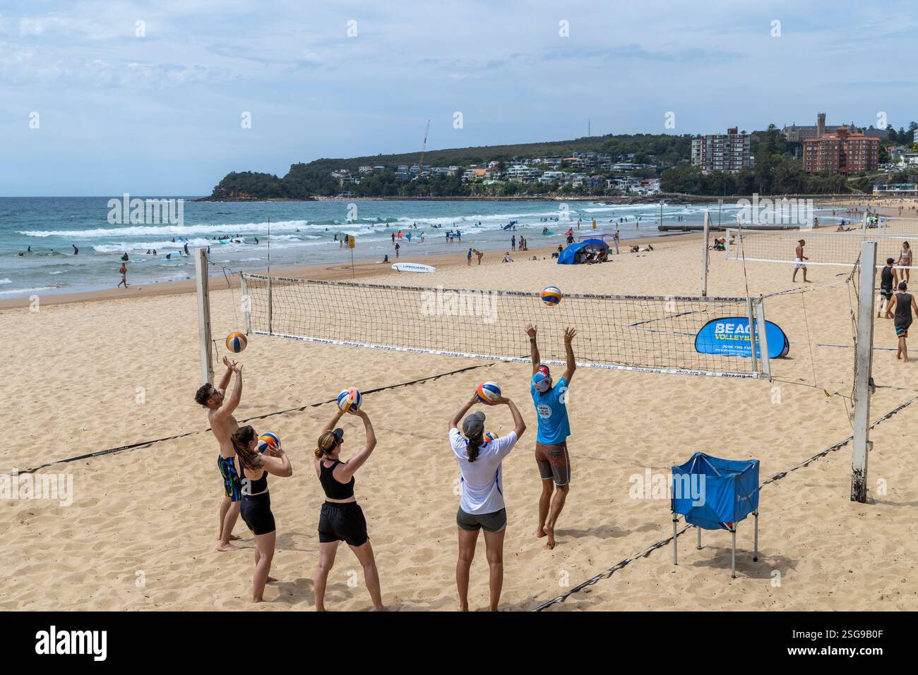 Cours de volley-ball de plage, sur Manly Beach à Sydney entraîneur de volley-ball donne des leçons sur le maniement du ballon à un groupe de joueurs débutants, NSW, Australie Banque D'Images