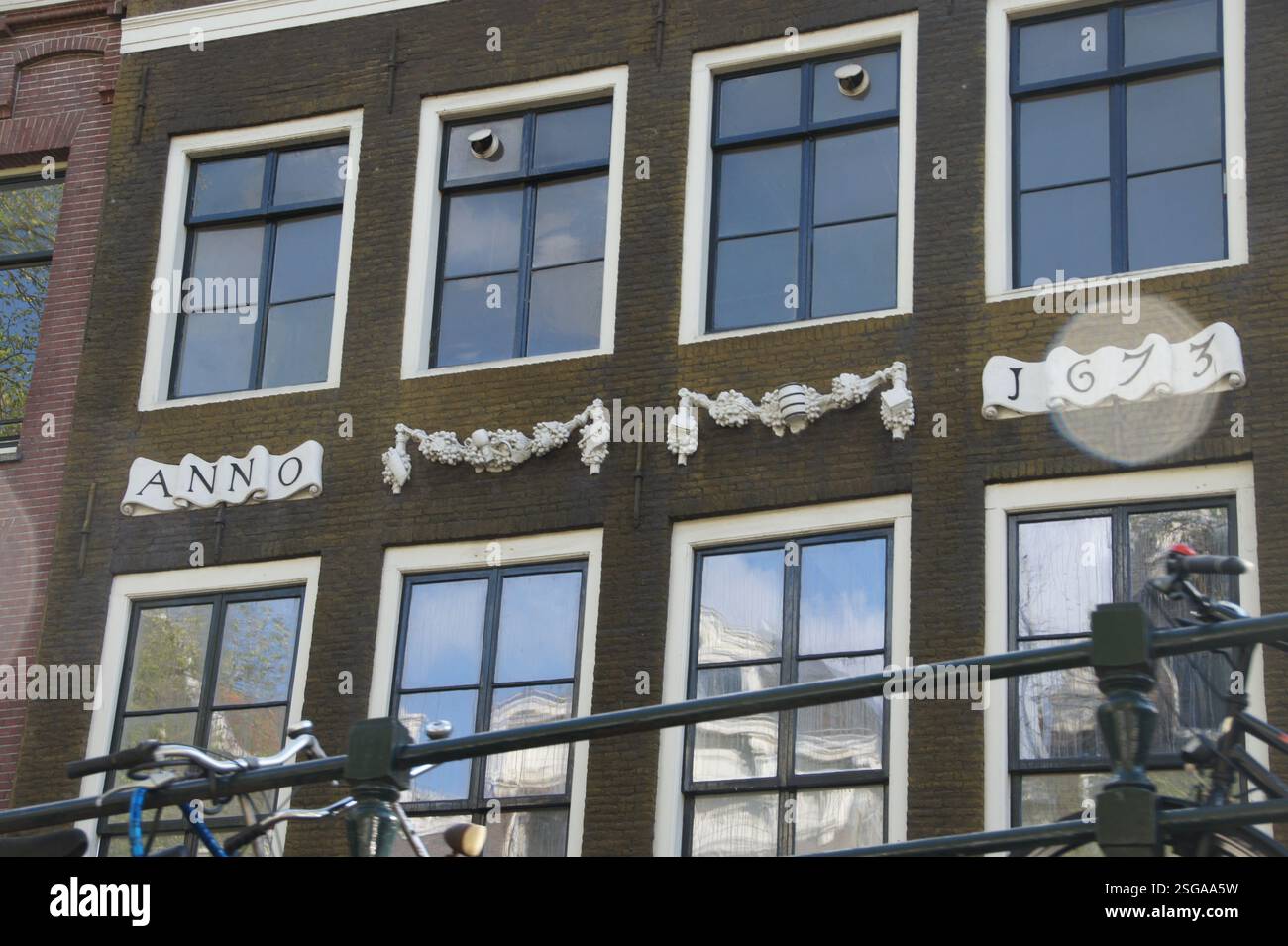 Un bâtiment historique en briques borde les pittoresques canaux d'Amsterdam. Un vélo seul se trouve garé devant, évoquant la culture cycliste de la ville. L'emplacement Banque D'Images